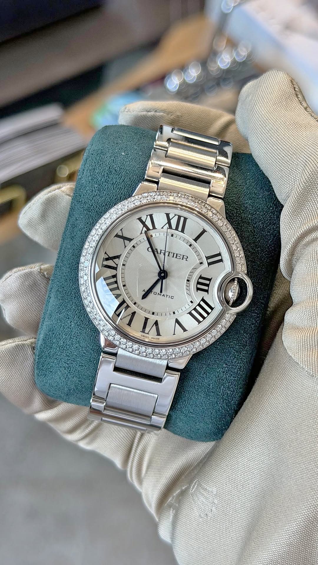 A diamond-bezel Cartier Ballon Bleu presented on a teal cushion